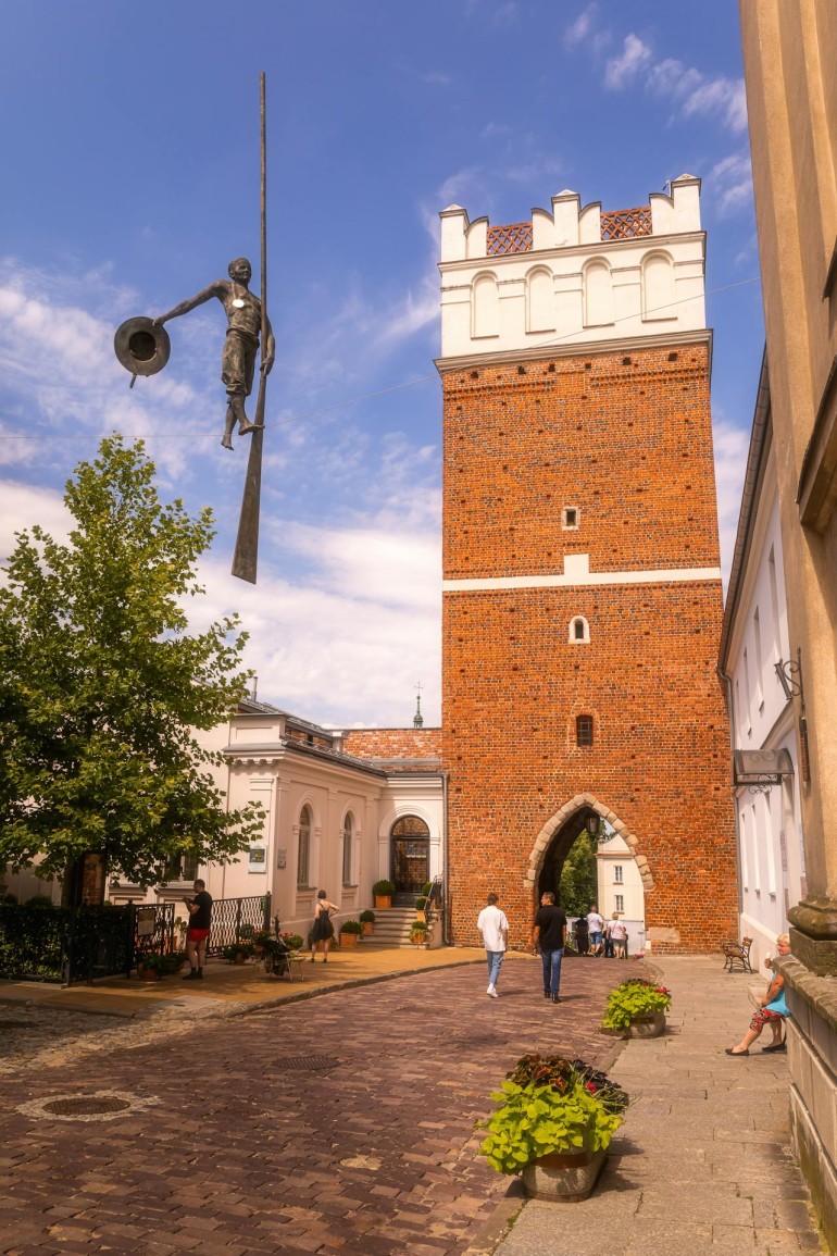 Brama Opatowska w Sandomierzu z balansującą rzeźbą flisaka